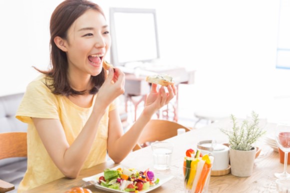 美味しそうにパンを食べている女性の画像